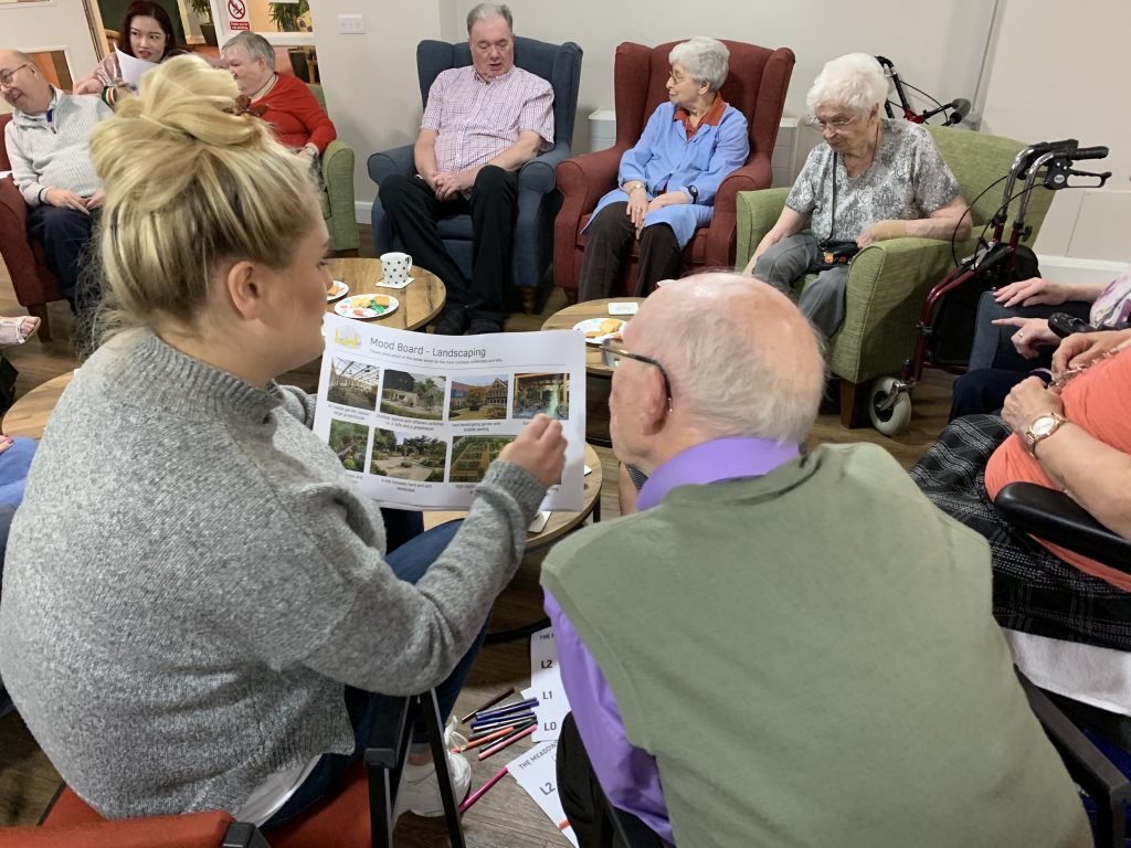 an image of a group of elderly people being shown a mood board on paper. 